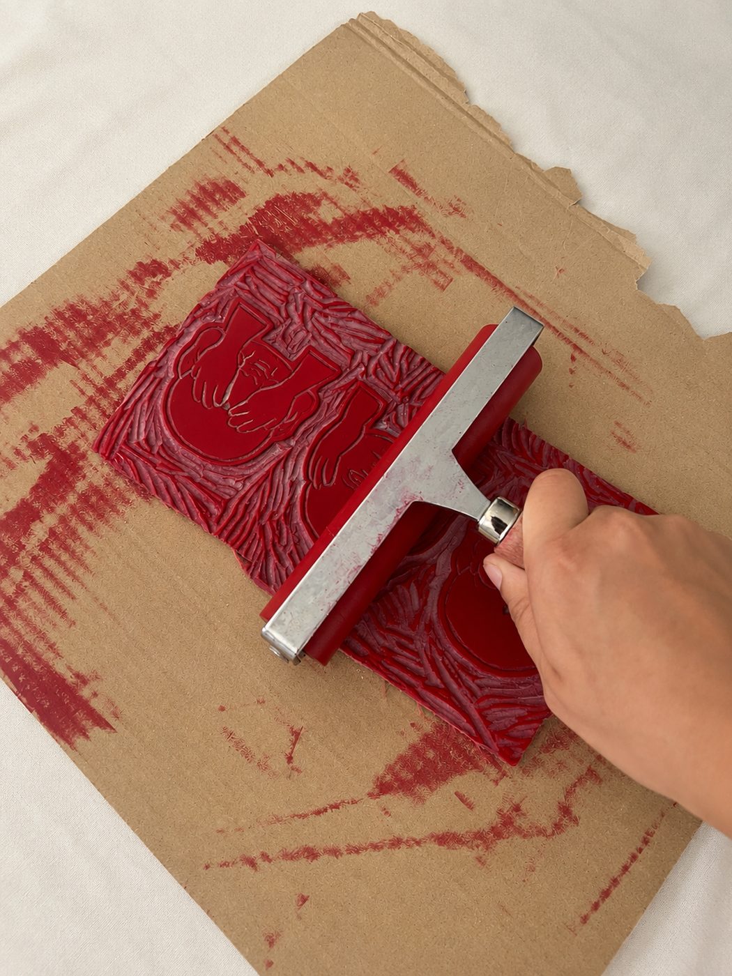 Pasando el rodillo con tinta roja sobre el bloque tallado